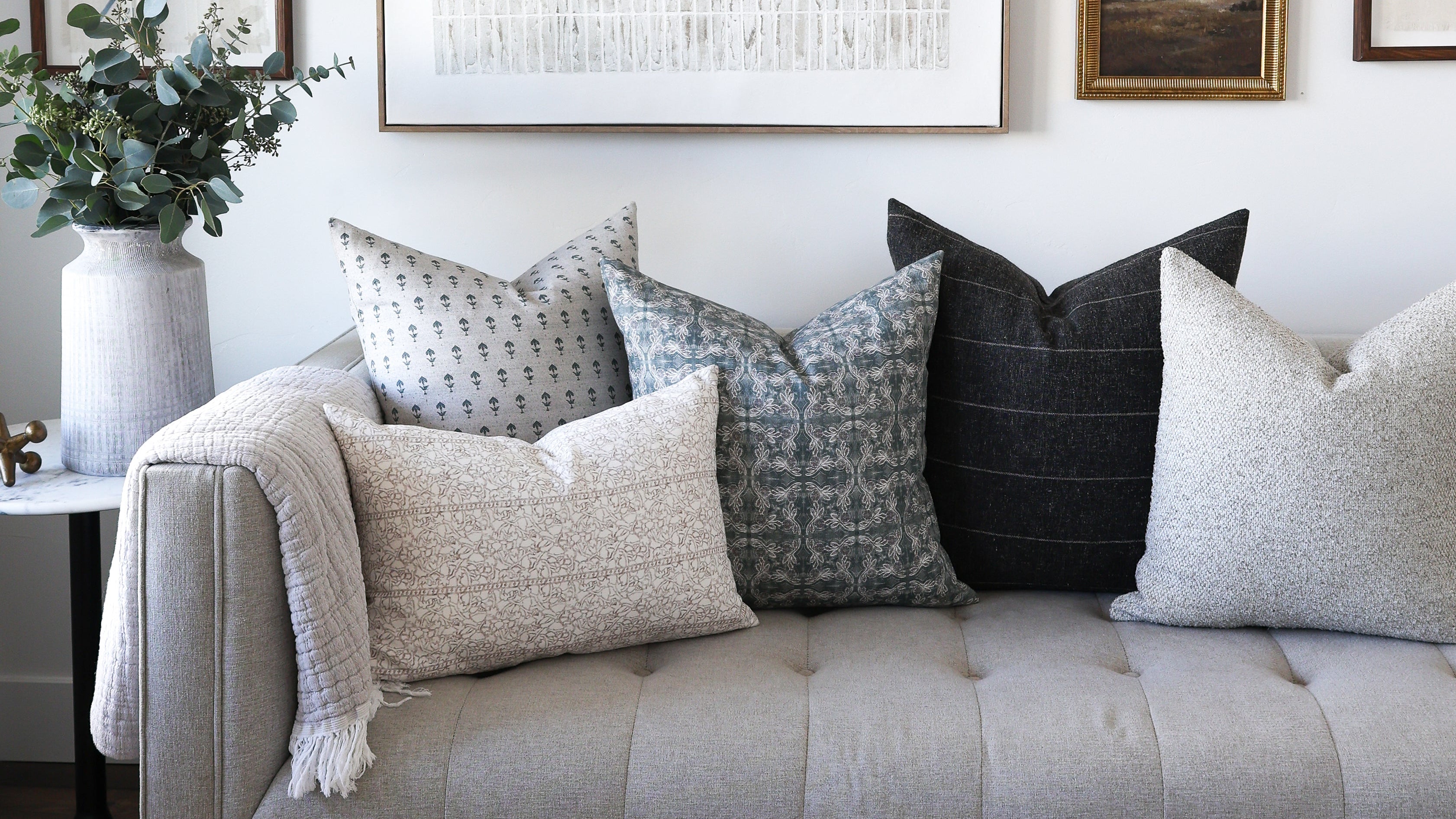 Living room with a gray sofa, decorative pillows, and framed artwork on the wall.