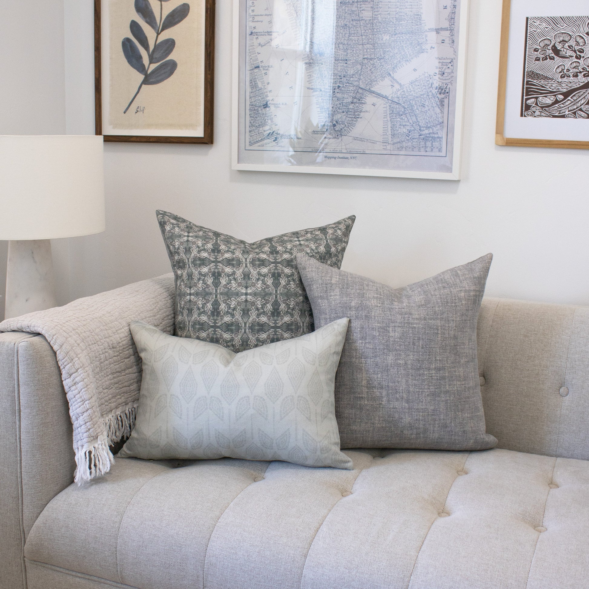 Gray sofa with patterned cushions against a wall with framed artwork