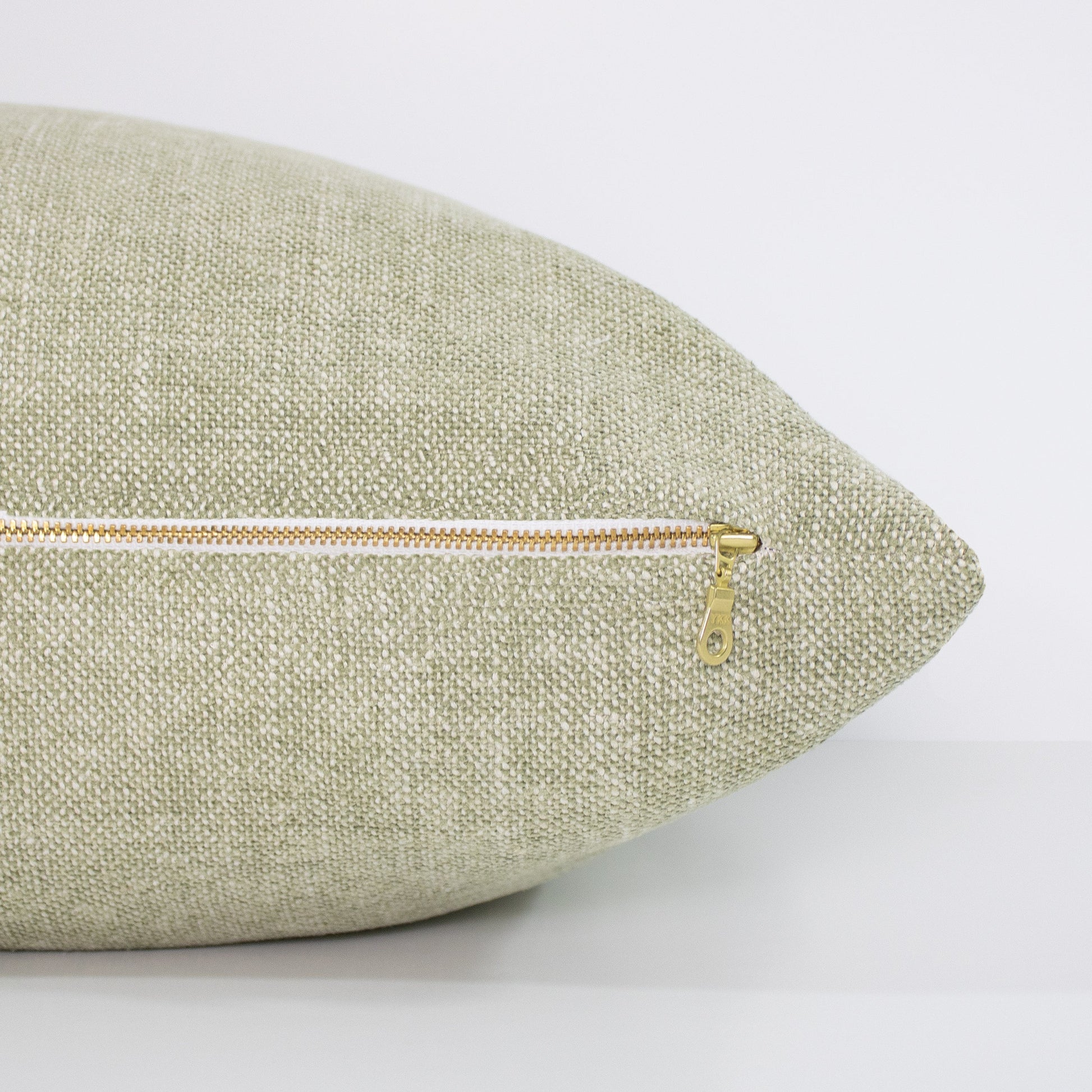 Green textured pillow with a zipper on a white background