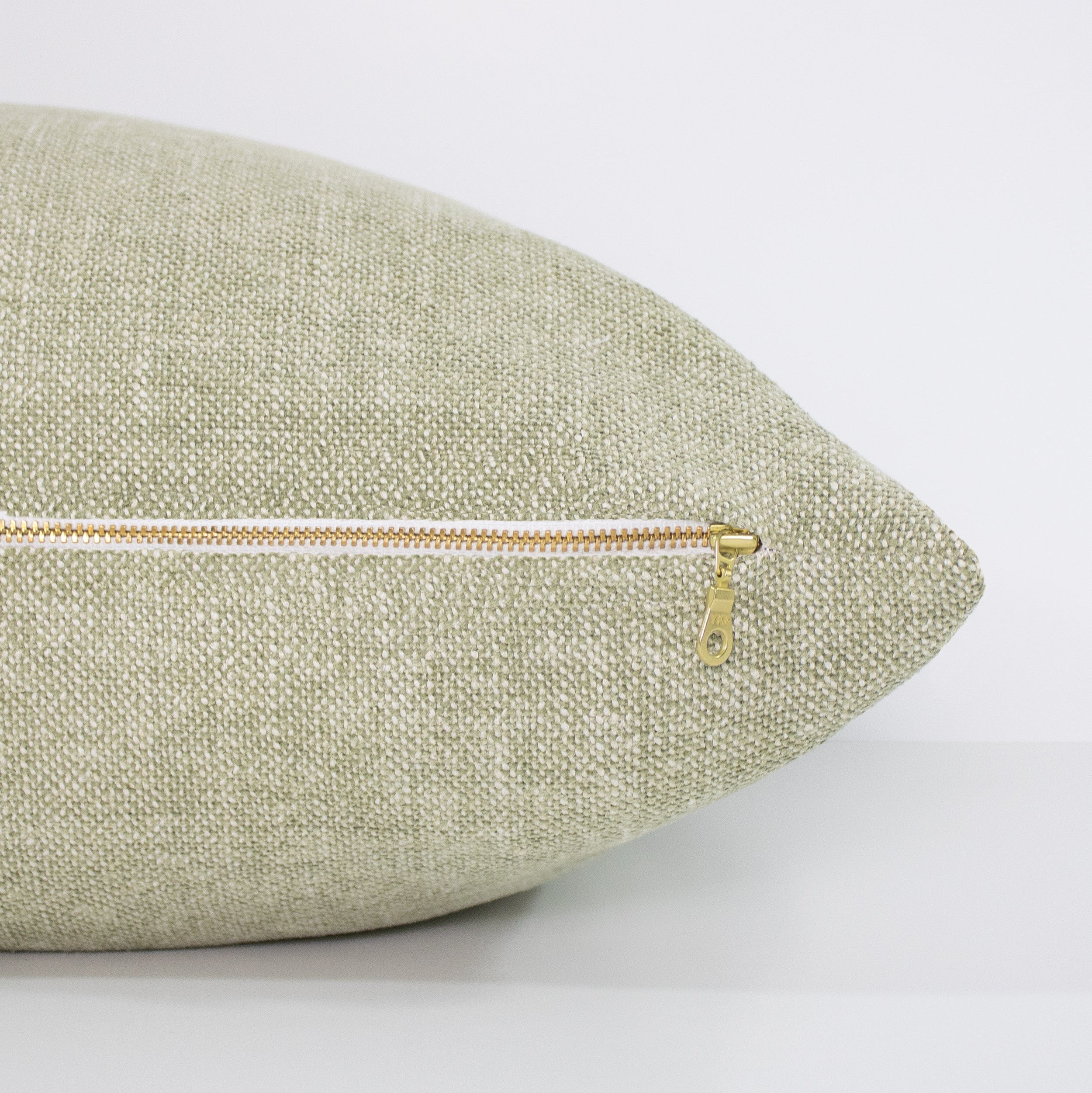Green textured pillow with a zipper on a white background