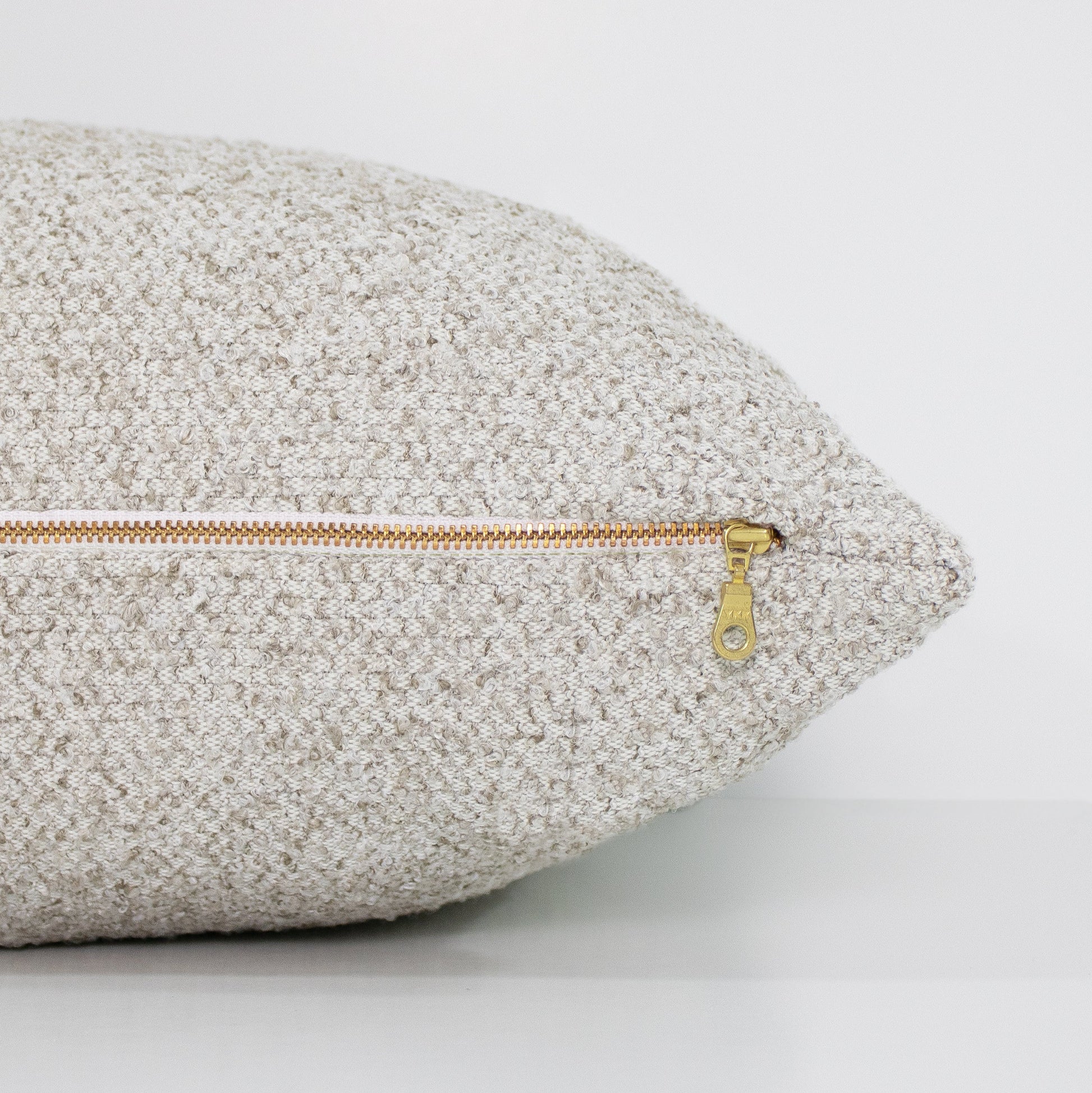 Textured pillow with a gold zipper on a light gray background