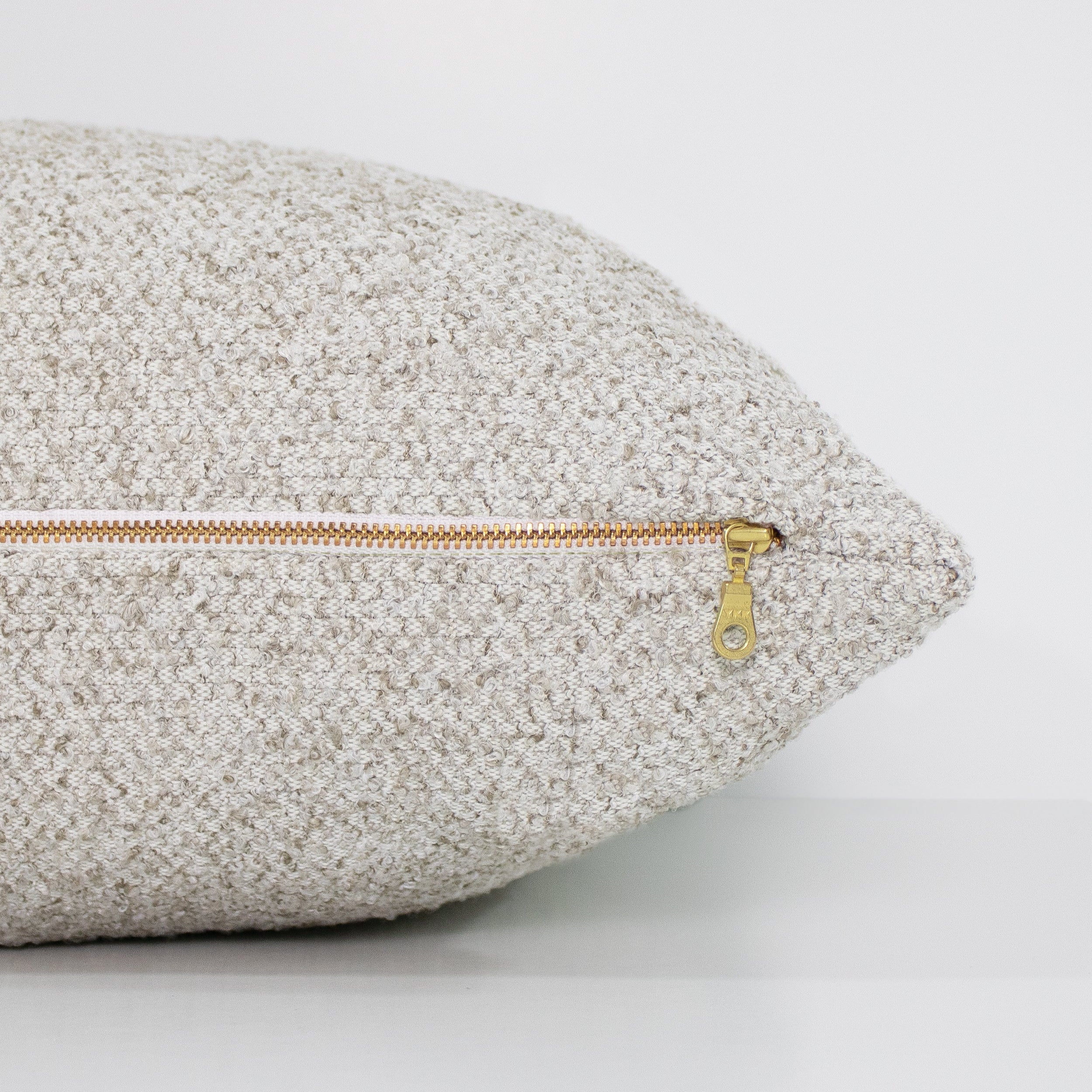 Textured pillow with a gold zipper on a light gray background