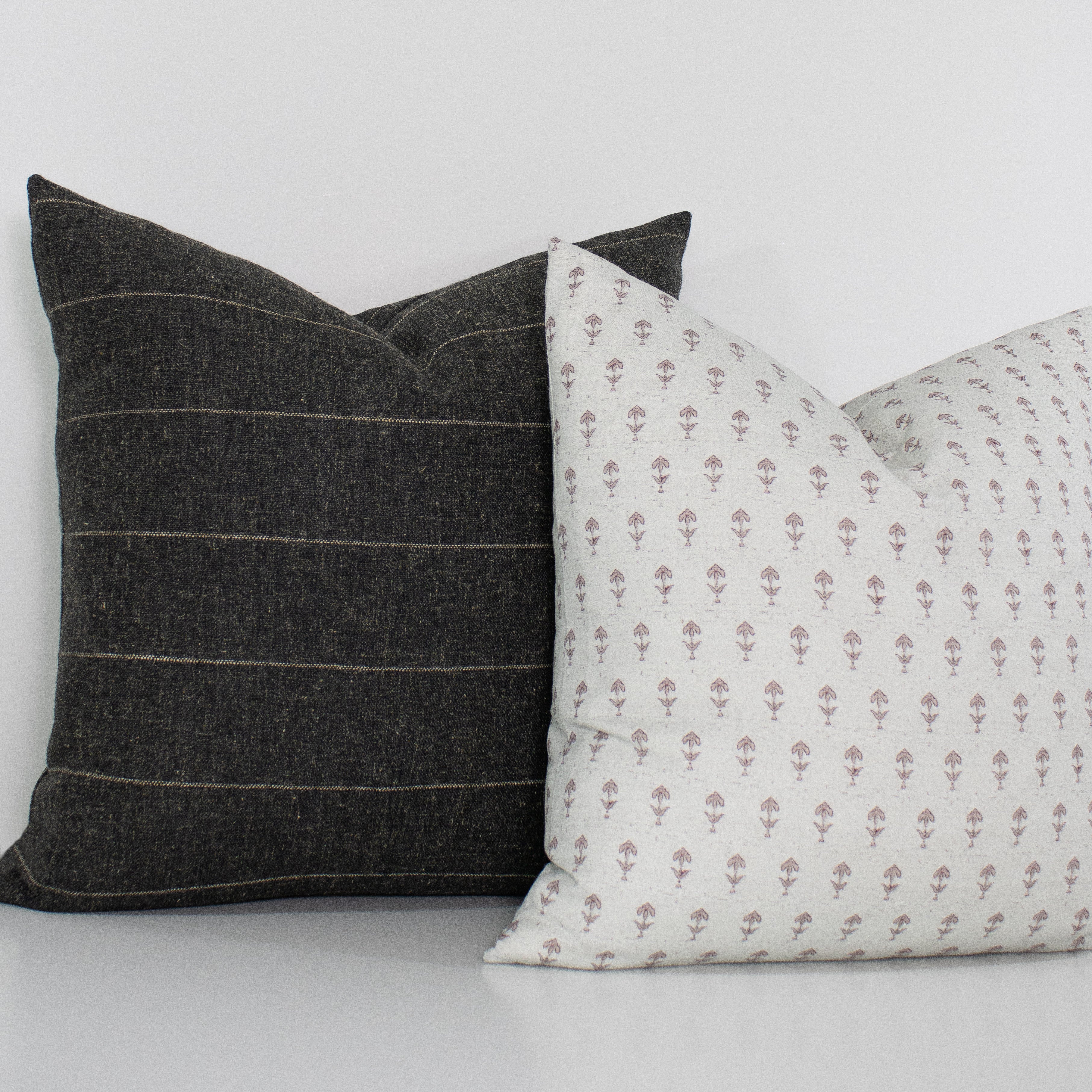 Two pillows, one with a striped pattern and the other with a floral pattern, on a light background.
